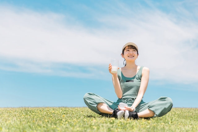 カルピスを片手に持つ女性の画像